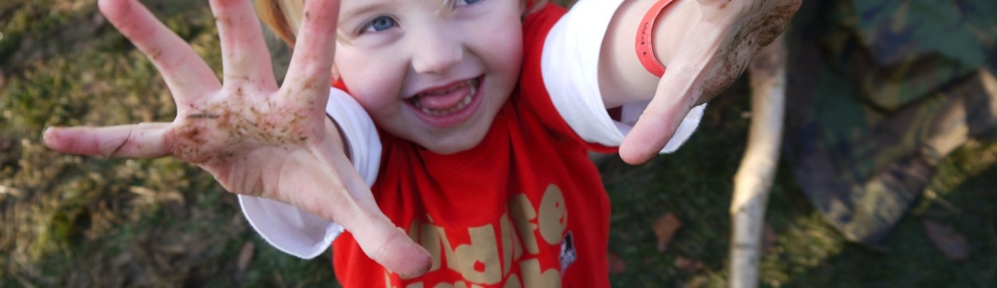smiling child with muddy hands